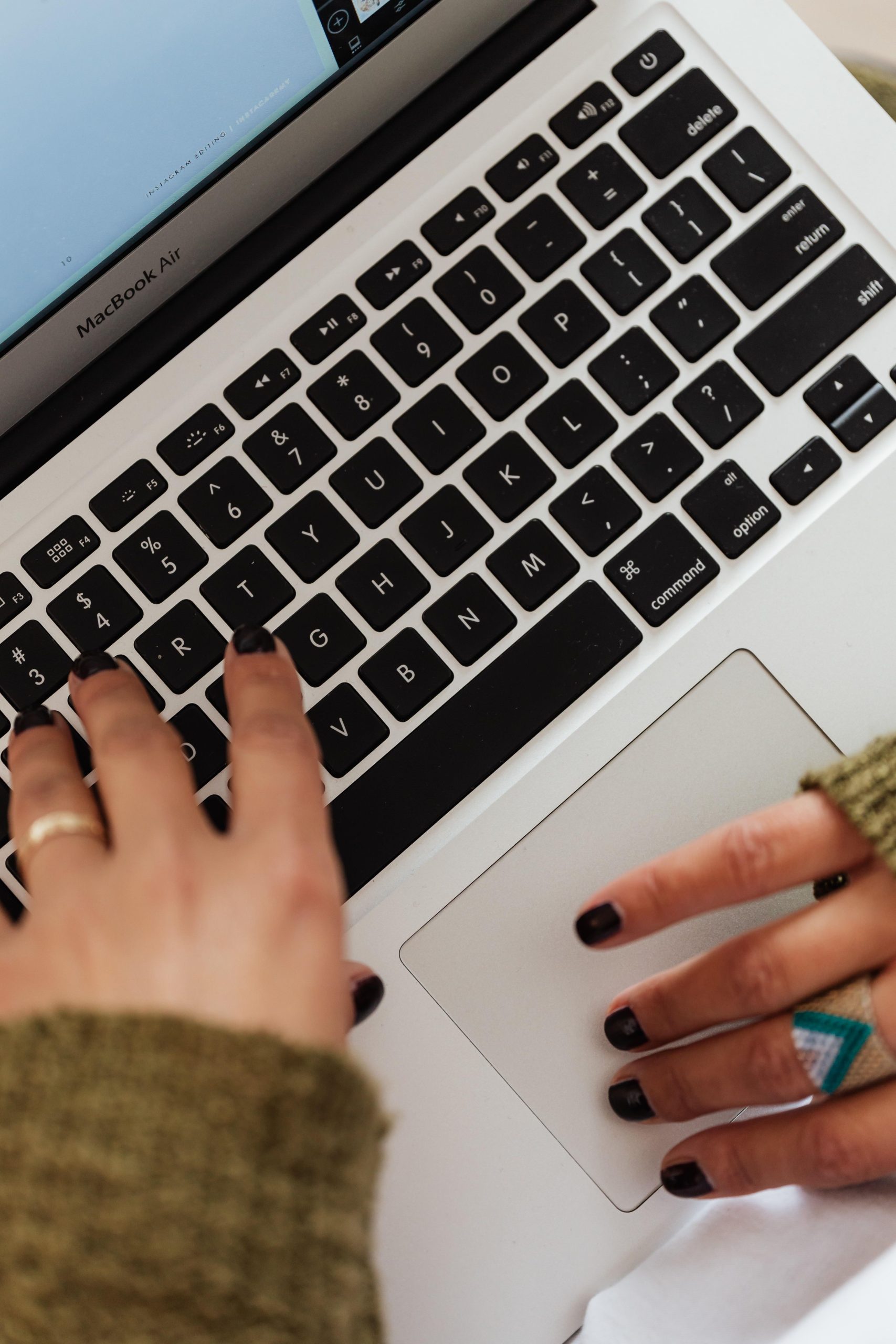 Close-up of hands typing on a laptop keyboard, representing AI-assisted writing