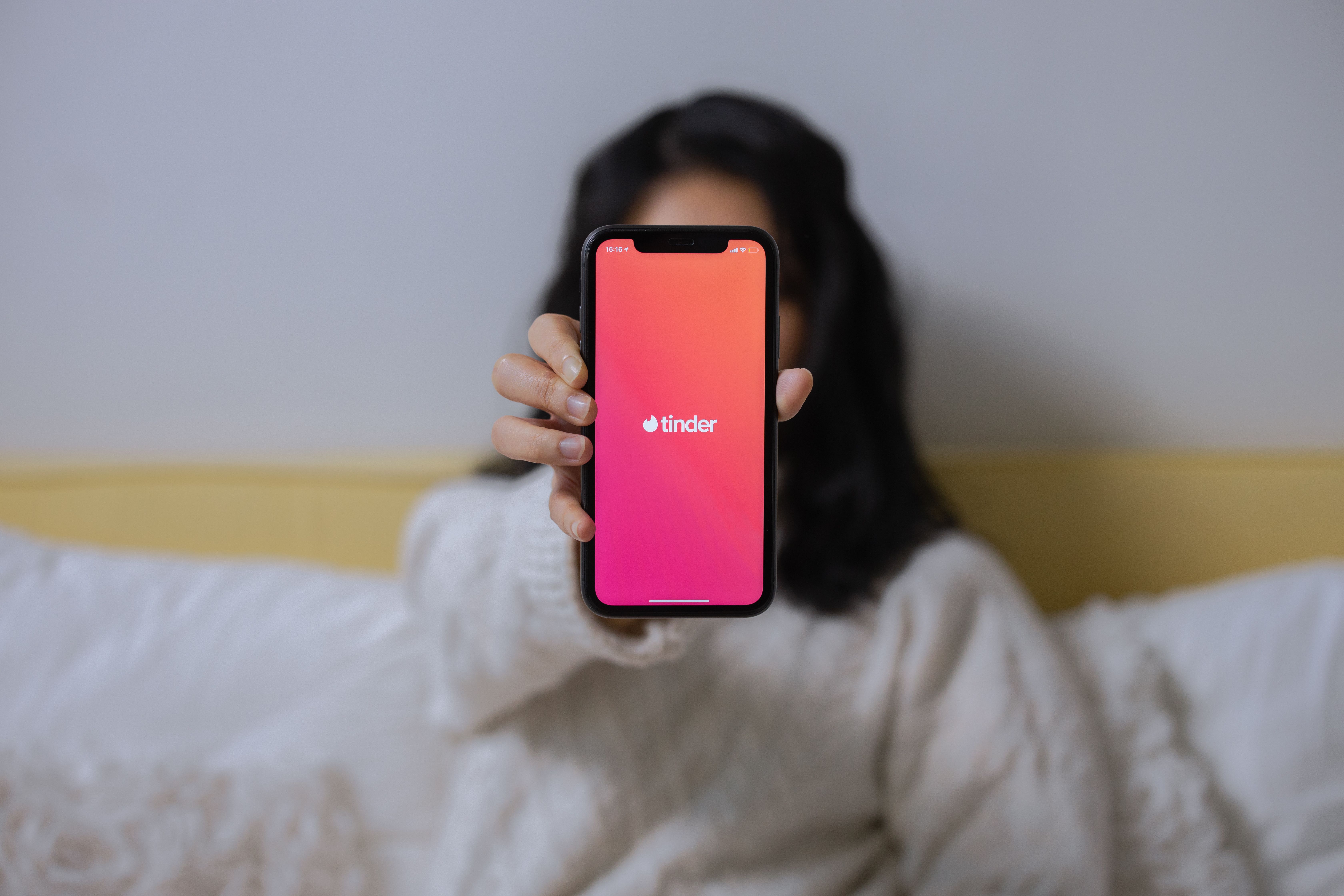 A woman checks a dating app on her smartphone, representing app-based connections and the market for romantic attention.