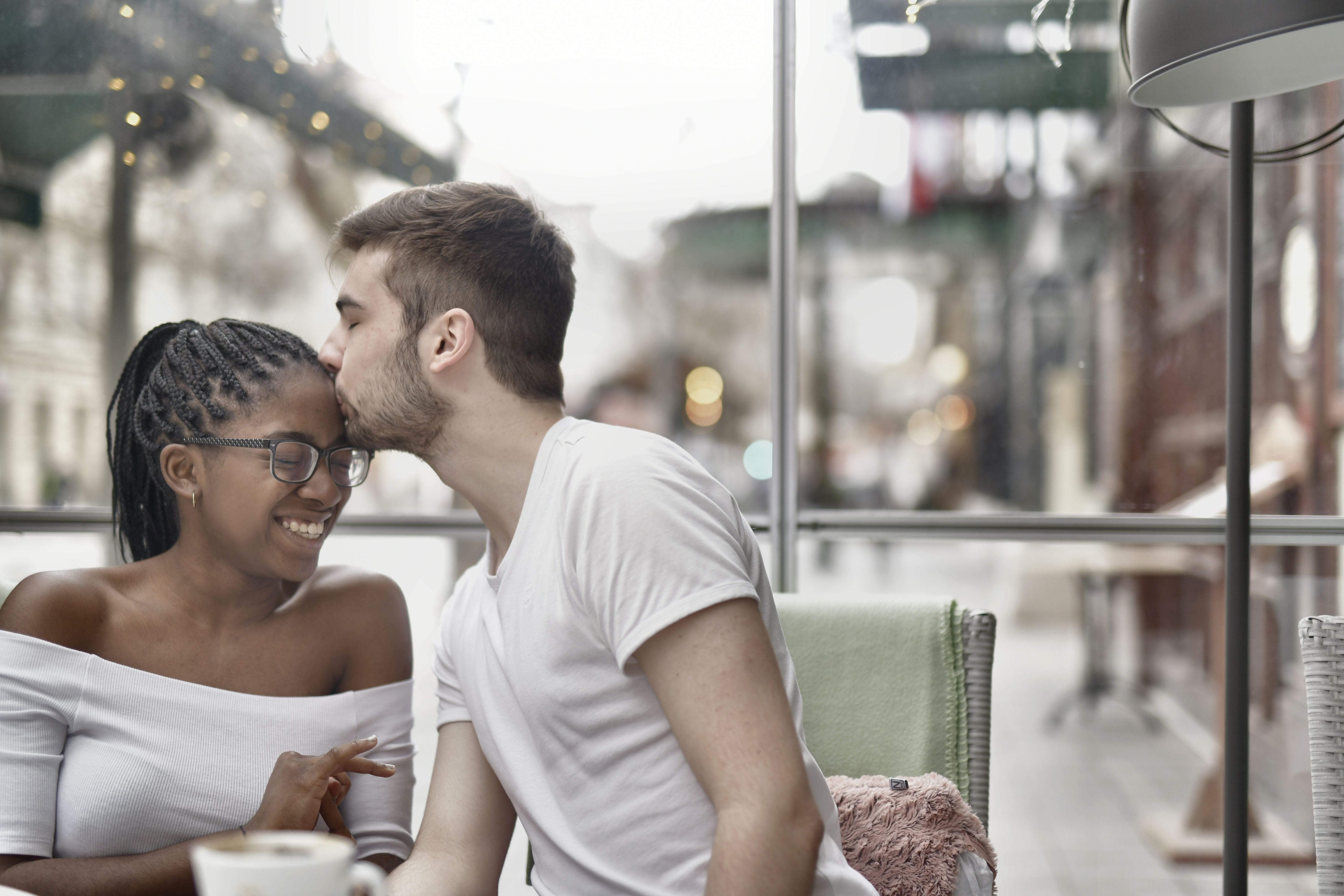 A couple shares a warm moment at a cafe, evoking the attentive conversation and intimacy associated with a girlfriend or boyfriend experience.